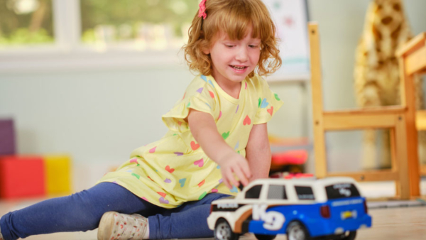 Niña jugando con un camión de juguete.